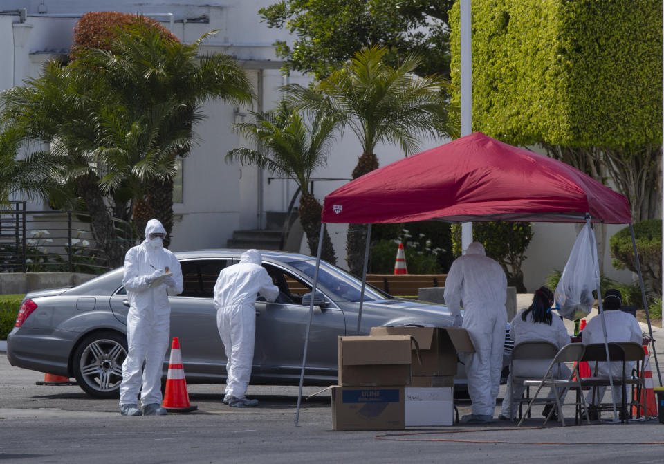 Unidentified Los Angeles residents are admistered with a test for COVID-19 while in their vehicles inside the Crenshaw Christian Center in South Los Angeles Wednesday, March 25, 2020. With California virus cases surging, Gov. Gavin Newsom said his stay-at-home order for 40 million Californians may stay in place into May. (AP Photo/Damian Dovarganes)