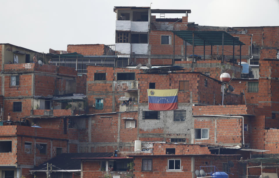 A Venezuelan flag hangs from a home in the Cotiza neighborhood where anti-government protesters clash with security forces after an apparent mutiny by a national guard unit in Caracas, Venezuela, Monday, Jan. 21, 2019. (AP Photo/Fernando Llano)