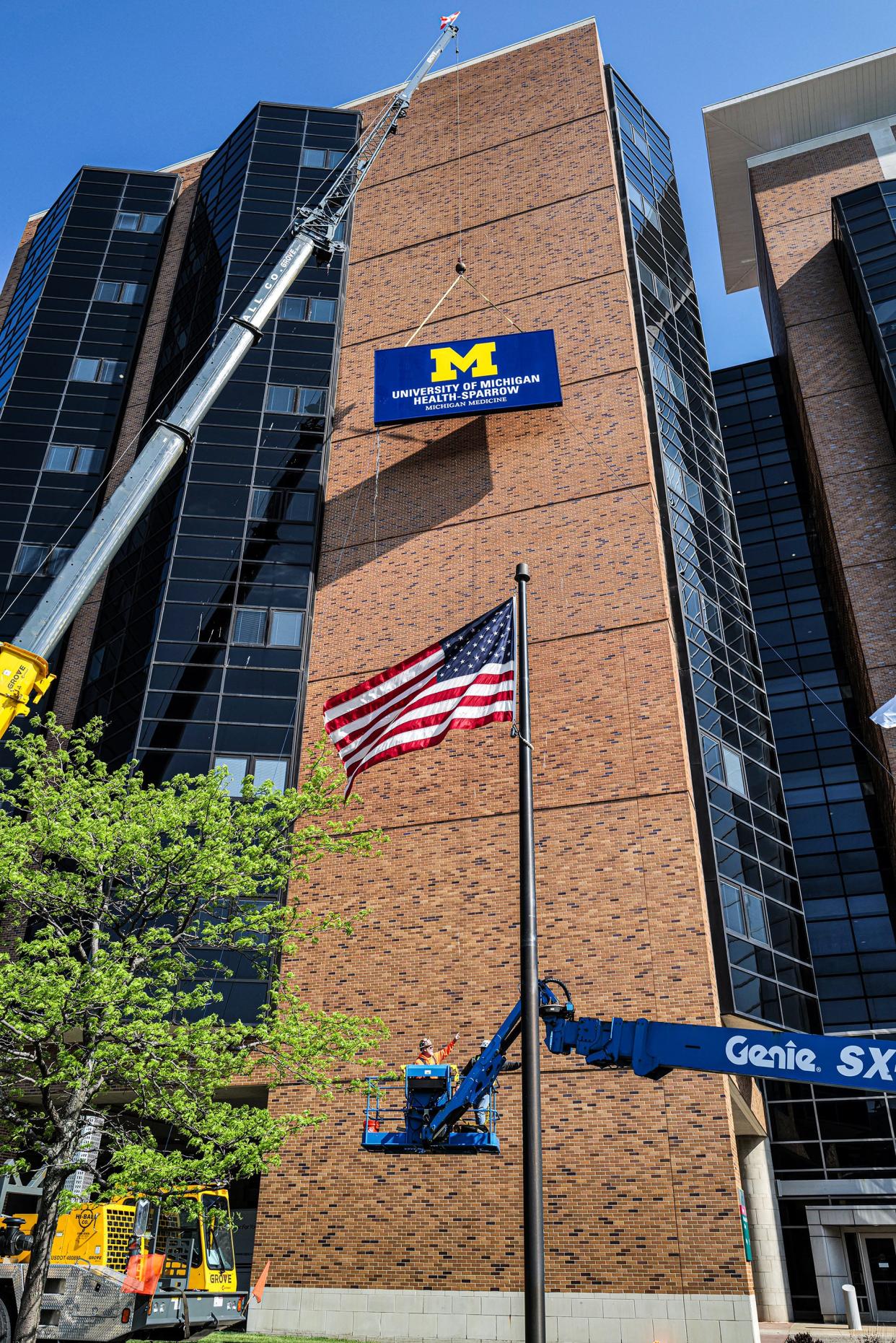 Contractors work on installing the University of Michigan Health-Sparrow sign near the top of Sparrow Hospital in Lansing Saturday, May 4, 2024.