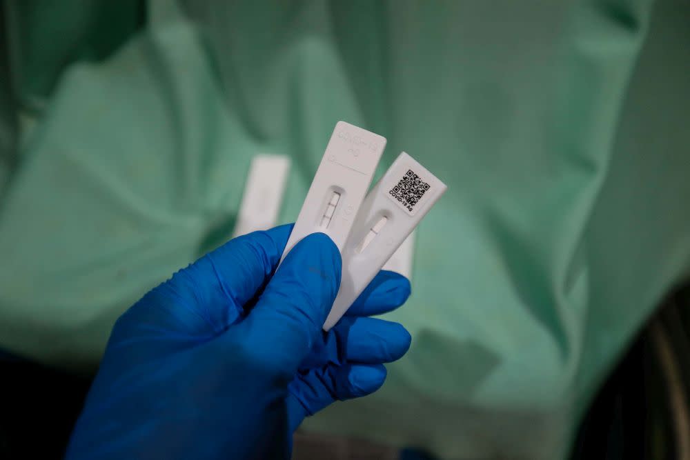 A health personnel holds up Covid-19 test strips indicating a positive and negative result in Seberang Jaya April 7, 2022. — Picture by Sayuti Zainudin