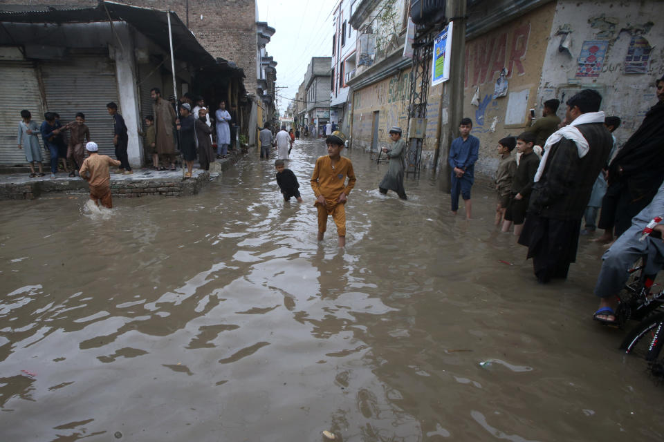 Youngsters wade through a flooded street caused by heavy rain in Peshawar, Pakistan, Monday, April 15, 2024. Lightening and heavy rains killed dozens of people, mostly farmers, across Pakistan in the past three days, officials said Monday, as authorities declared a state of emergency in the country's southwest following an overnight rainfall to avoid any further casualties and damages. (AP Photo/Muhammad Sajjad)