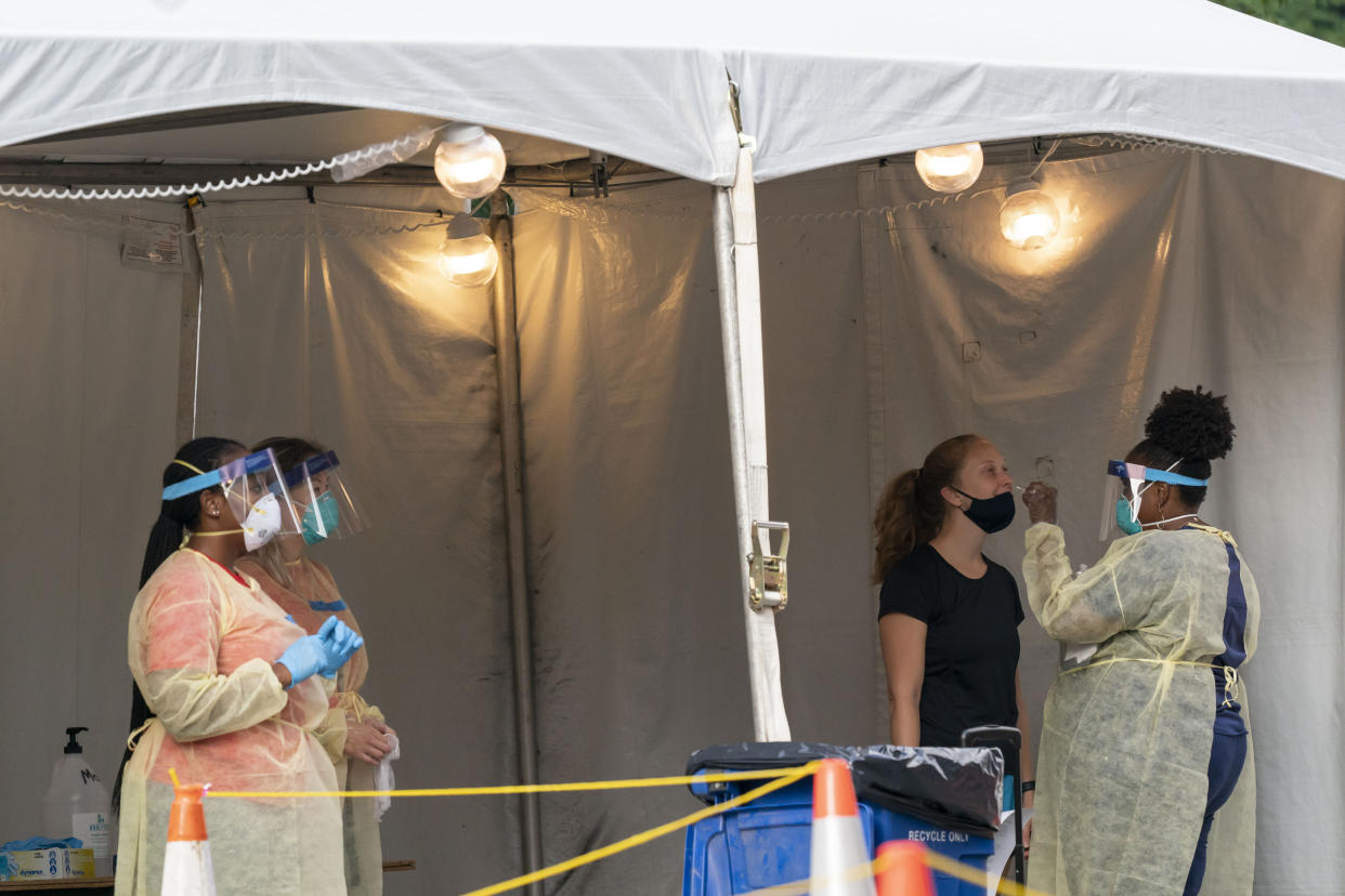 A nurse with the Washington, D.C. Dept. of Health, administers a COVID-19 test on F Street, Aug. 14, 2020, in Washington. This location tests approximately 450-500 people a week and has been open since June 1st. (AP Photo/Alex Brandon)