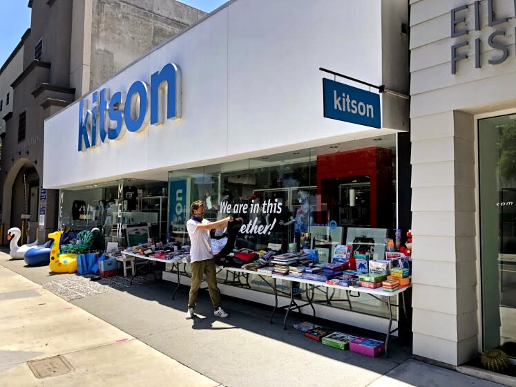 LOS ANGELES, CALIF. - MAY 11, 2020 - Kitson employee Tom Ernst rearranges merchandise displayed to attract walk-by customers on Robertson Boulevard in Los Angeles. While some employees around the U.S. have been squeamish about returning to face to face retail work, Ernst is thrilled to feel needed again and have a place to go outside his home. "It's been so great to be back to work," he said. (Ronald D. White / Los Angeles Times)