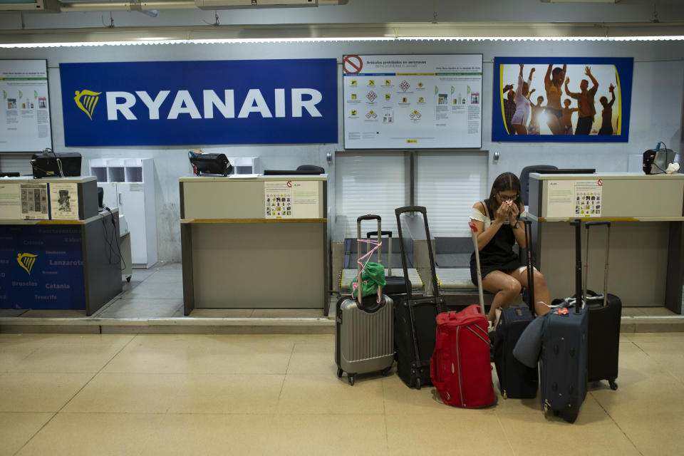 A Portuguese woman, who preferred not to give her name, sits at a Ryanair airline check-in desk after her flight to Pisa, Italy, was cancelled during the first of two days cabin crew strike at Adolfo Suarez-Barajas international airport in Madrid, Wednesday, July 25, 2018. Low-cost airline Ryanair cabin crew are to stage a 48-hour strike July 25 and 26 in Spain, Portugal, Italy and Belgium. (AP Photo/Francisco Seco)