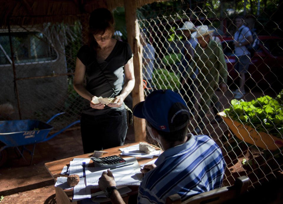 In this Dec. 8, 2012 photo, U.S. chef Kelsie Kerr pays for produce at a farm in Havana, Cuba. Kerr traveled to Cuba with the "Planting Seeds" delegation that held give-and-take seminars with chefs and culinary students about slow food. Cuba has a longstanding culture of organic farming by necessity. During the "Special Period" of the 1990s, many private urban plots popped up in Havana amid austerity after the collapse of the Soviet Union. Unlike in the United States, pesticide-free is largely the rule here rather than the exception, mostly due to a lack of supply. (AP Photo/Ramon Espinosa)