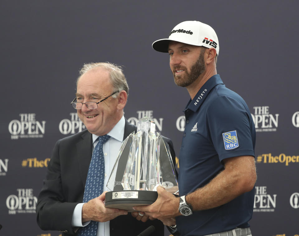 Dustin Johnson of the United States, right, receives The Mark H McCormack award for being the leading playing in the Official World Golf rankings for 2018, from OWGR Chairman Peter Dawson during a ceremony ahead of the British Open golf championships at Royal Portrush in Northern Ireland, Tuesday, July 16, 2019. The British Open starts Thursday. (AP Photo/Jon Super)