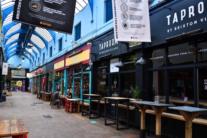 A couple sit among empty tables during a quiet night at Brixton Village in London