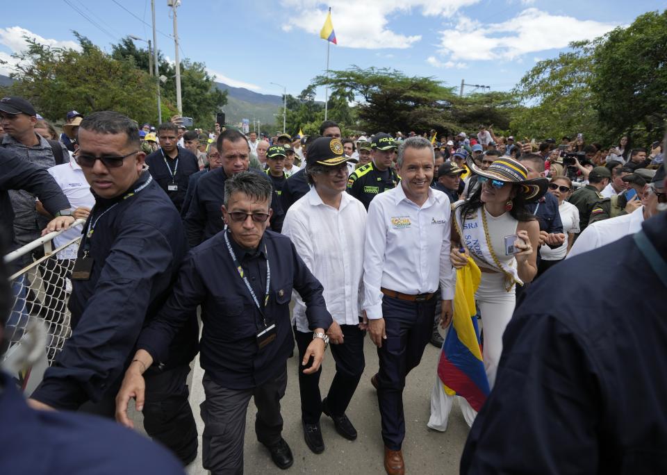 Colombia's President Gustavo, center left wearing cap, walks on the Simon Bolivar International Bridge after a ceremony marking its reopening to cargo trucks between Cucuta, Colombia and San Antonio del Tachira, Venezuela, Monday, Sept. 26, 2022. Vehicles with merchandise will cross the bridge on Monday in a ceremonial act to seal the resumption of commercial relations between the two nations. (AP Photo/Fernando Vergara)