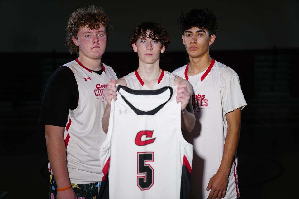 Three of Preston Lord's close friends hold his jersey at Combs High School. Lord was to be a varsity member of the team but was attacked and left lying on the street after a party. He died two days later, on Oct. 30.