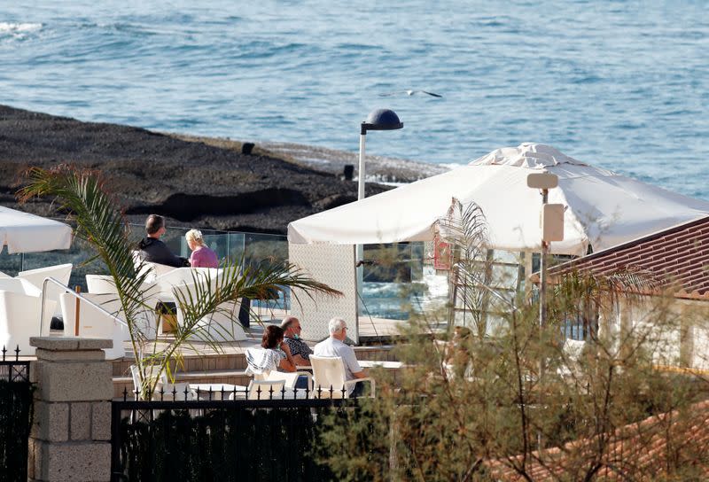 Tourists sit on the terrace of the H10 Costa Adeje Palace hotel, which is on lockdown after novel coronavirus has been confirmed in Adeje