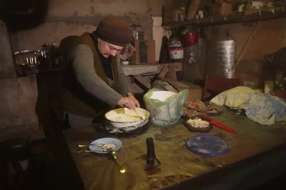 Ludmyla, 70, makes a potato cake for the people sharing her makeshift shelter in the war-torn city of Bakhmut. (Dean Taylor / NBC News)