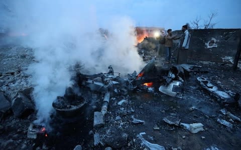 Syrian men standing at the site of a downed Sukhoi-25 fighter jet in the the Syrian city of Saraqib, southwest of Aleppo.  - Credit: AFP