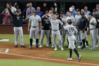 New York Yankees' Aaron Judge (99) approaches home plate as teammates come out to congratulate him after hitting a solo home run, his 62nd of the season, in the first inning of the second baseball game of a doubleheader against the Texas Rangers in Arlington, Texas, Tuesday, Oct. 4, 2022. With the home run, Judge set the AL record for home runs in a season, passing Roger Maris. Umpire Randy Rosenberg and Rangers catcher Sam Huff also stand by watching the play. (AP Photo/Tony Gutierrez)