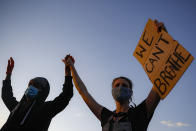 Protestors demonstrate on University Avenue while holding a "WE CAN'T BREATHE" sign and wearing protective masks, Thursday, May 28, 2020, in St. Paul, Minn. Protests over the death of George Floyd, a black man who died in police custody Monday, broke out in Minneapolis for a third straight night. (AP Photo/John Minchillo)