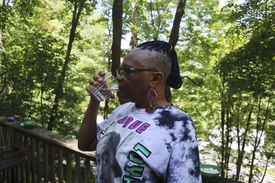 Donna Dickerson drinks a cup of tap water on the porch of her trailer in Keystone, W.Va., on June 22, 2022. For about a decade before being hooked up to a new water system late last year, residents of Keystone like Dickerson were told to boil water before drinking it for a decade because of the community's aging infrastructure. (AP Photo/Leah Willingham)
