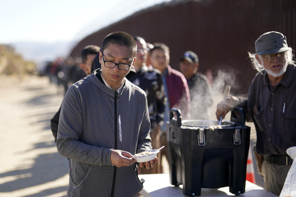 A man from China gets a bowl of oatmeal from a volunteer as he waits with others for processing to apply for asylum after crossing the border with Mexico, Tuesday, Oct. 24, 2023, near Jacumba, Calif. A major influx of Chinese migration to the United States on a relatively new and perilous route through Panama's Darién Gap jungle has become increasingly popular thanks to social media. (AP Photo/Gregory Bull)