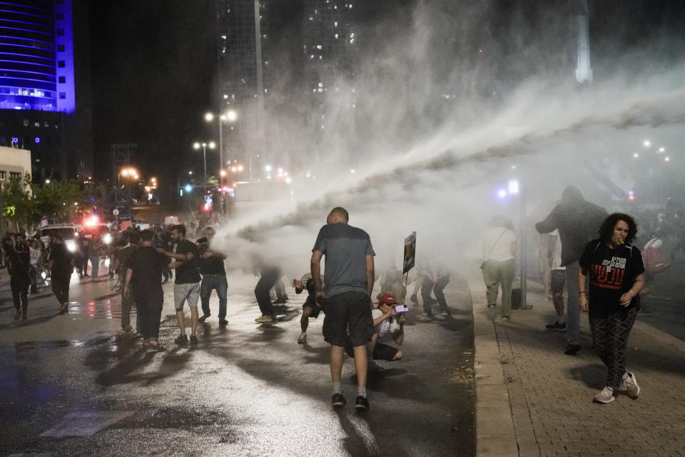Police use water cannon to disperse demonstrators blocking a road during a protest against Israeli Prime Minister Benjamin Netanyahu's government, and calling for the release of hostages held in the Gaza Strip by the Hamas militant group, in Tel Aviv, Israel, Saturday, May 18, 2024. (AP Photo/Leo Correa)