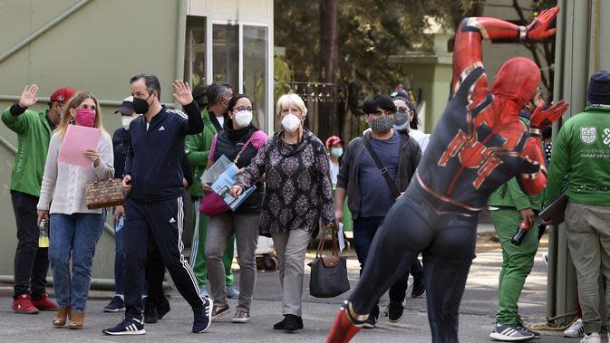Seorang pria yang mengenakan kostum Spiderman menyapa orang-orang setelah mereka disuntik vaksin covid-19 Pfizer-BioNTech di Mexico City, Meksiko, Selasa (28/12/2021). Spiderman tersebut dipekerjakan oleh Pemerintah Kota untuk menghibur para peserta vaksinasi. (ALFREDO ESTRELLA / AFP)