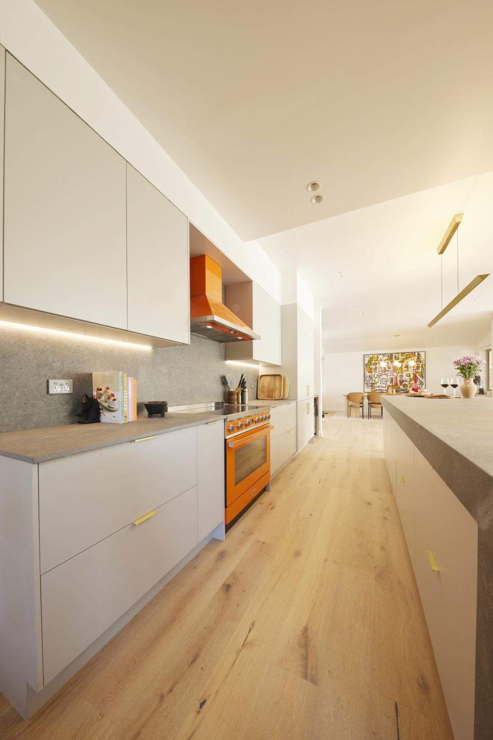 A shot of the kitchen, with the orange stove and range hood on the left and kitchen island on the right. 