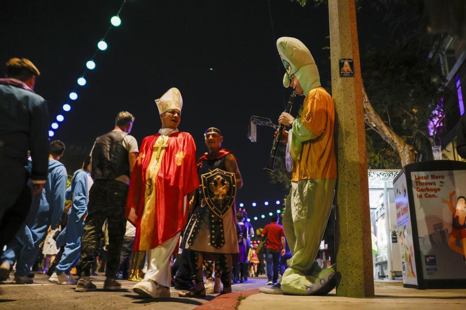 Justin Marchert as "Squidward," plays a clarinet as Halloween revelers pass by.