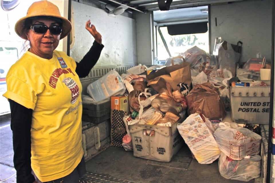 A letter carrier stands next to truck with food collected through the 2018 "Stamp Out Hunger" Food Drive.