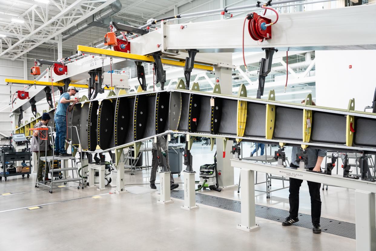 Workers check over a wing in the final assembly jig at Beta Technologies' new production facility in South Burlington.