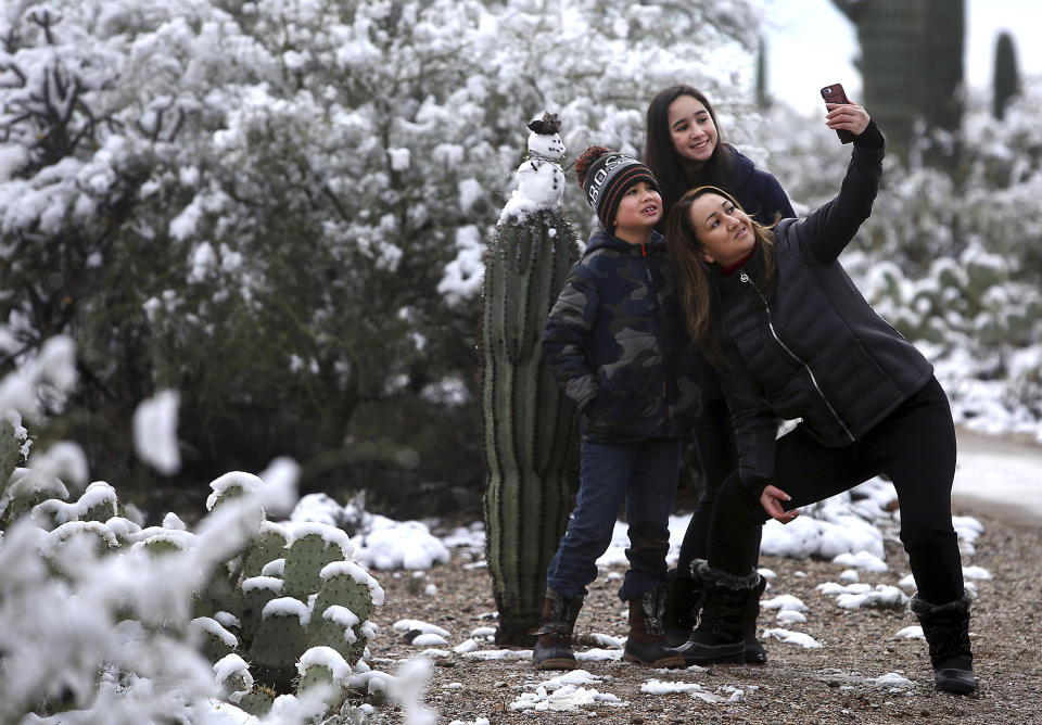 "It's the first time we've seen snow the desert," says Mayra Vasquez who brought Valeria Luzania, 11, and MarcoDario Luzania, 8, to Saguaro National Park East on January 02, 2019. The kids built a snowman and the trio took a selfie with their creation. Parts of the Old Pueblo woke up to snow on New Year's Day, followed by more snow Wednesday morning. (Mamta Popat /Arizona Daily Star via AP)