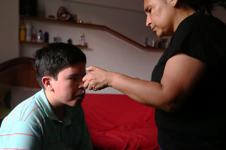 Ana Alvarez gives her son Anthony a spoonful of marijuana oil to soothe the symptoms of tuberous sclerosis and Lennox-Gastaut syndrome at her house in Lima, Peru, February 23, 2017. Picture taken February 23, 2017. REUTERS/Guadalupe Pardo