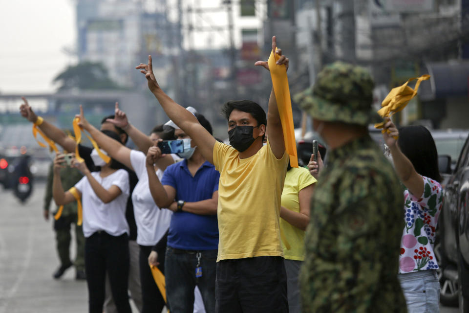 Supporters of former Philippine President Benigno Aquino III flash the "L" sign meaning "Fight!" during a motorcade before his burial in Quezon City, Philippines on Saturday, June 26, 2021. Aquino was buried in austere state rites during the pandemic Saturday with many remembering him for standing up to China over territorial disputes, striking a peace deal with Muslim guerrillas and defending democracy in a Southeast Asian nation where his parents helped topple a dictator. He was 61. (AP Photo/Basilio Sepe)