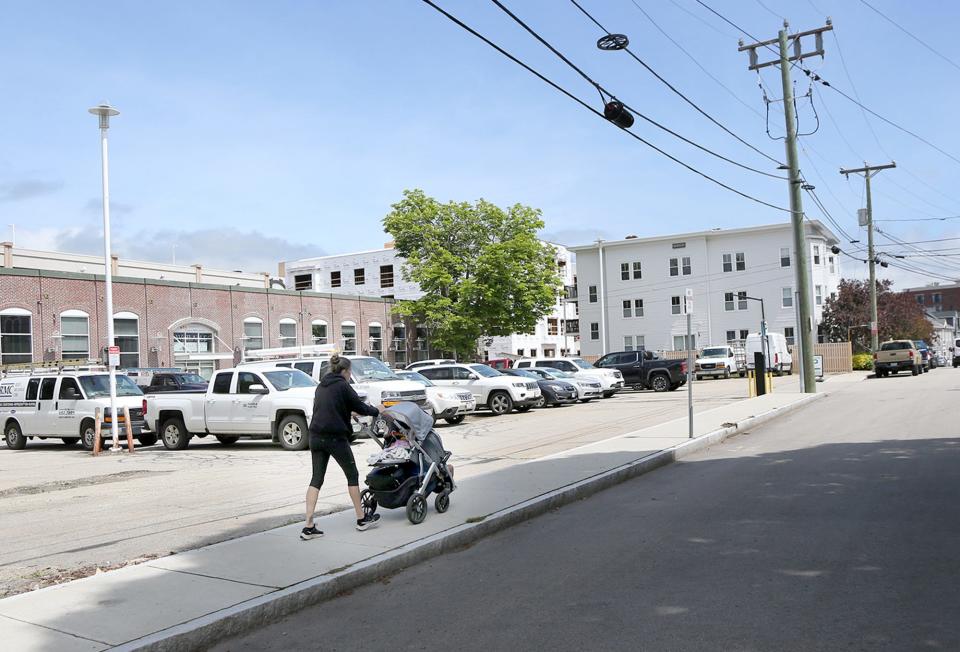 A mother pushing a carriage walks by 361 Hanover St. which was the former Heinemann Publishing building and once was the home of Portsmouth Steam Factory.