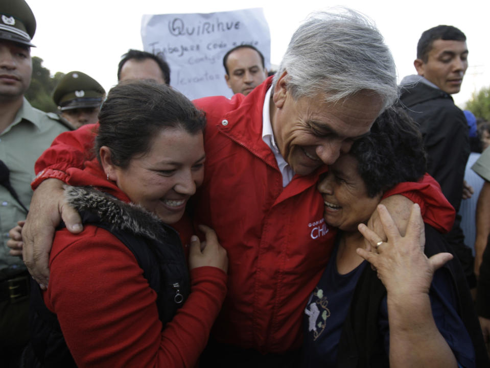 FILE - In this Saturday March 13, 2010 file photo, Chile's President Sebastian Pinera, center, hugs earthquake victims during a visit to a damaged area of Pelluhue, Chile. Chile marks the two-year anniversary on Monday Feb. 27, 2012 of the tsunami triggered by a magnitude-8.8 earthquake. (AP Photo/Martin Mejia, File)