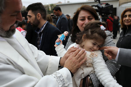 A priest plays with a child after a mass on Christmas at St George Chaldean Catholic Church in Baghdad, Iraq December 25, 2018. REUTERS/Thaier Al-Sudani