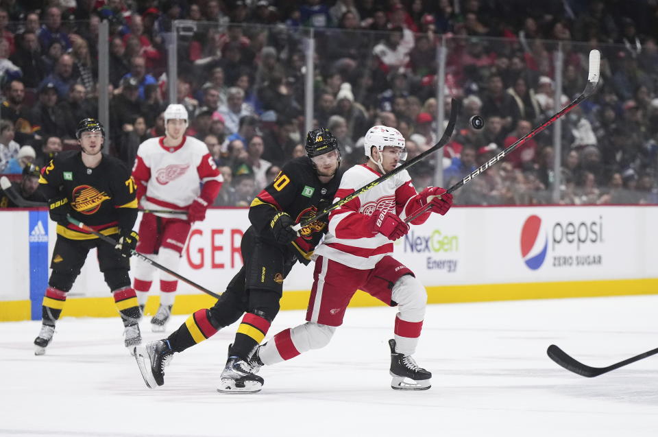 Vancouver Canucks' Elias Pettersson, front left, checks Detroit Red Wings' Pius Suter during the second period of an NHL hockey game in Vancouver, British Columbia, Monday, Feb. 13, 2023. (Darryl Dyck/The Canadian Press via AP)