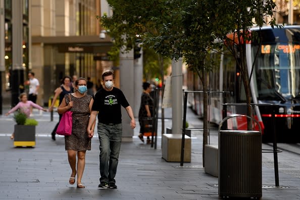 People wearing face masks walk in the empty streets of Sydney's central business district on Easter Saturday in Sydney.