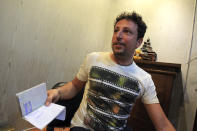 In this March 12, 2014 photo, Italian Luigi Maraldi whose stolen passport was used by a passenger boarding a missing Malaysia Airlines plane, shows his passport as he speaks to a reporter at Phuket police station in Phuket province, southern Thailand. Maraldi lost his passport when he hired a motorbike on Phuket last year. When he returned to the shop to retrieve his passport, he was told it had been given away to someone who looked just like him. His passport, along with another stolen in Phuket two years earlier, was used to board the ill-fated flight from Kuala Lumpur to Beijing undetected, revealing startling shortcomings in the security of international travel. Interpol said it maintains a global database of 40 million lost or stolen travel documents. The organization said only a handful of countries actually check the database before allowing passengers to board international flights. Malaysia and Thailand are not among them. (AP Photo/Sakchai Lalit)