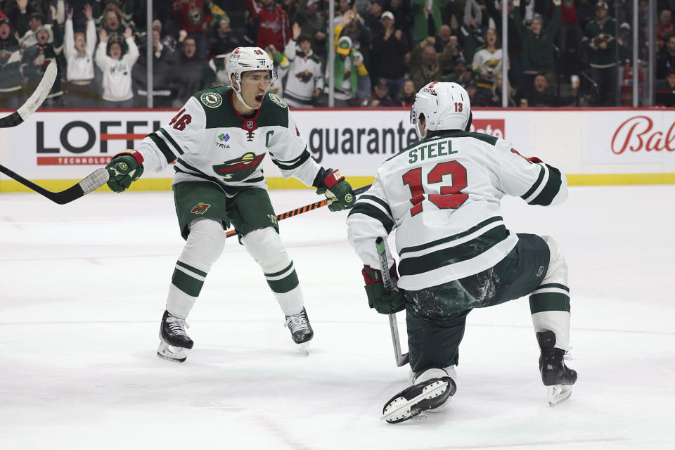 Minnesota Wild center Sam Steel (13) celebrates with defenseman Jared Spurgeon (46) after Steel scored a goal against the Carolina Hurricanes during the third period of an NHL hockey game Saturday, Nov. 19, 2022, in St. Paul, Minn. Minnesota won 2-1 in overtime. (AP Photo/Stacy Bengs)