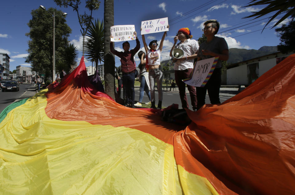 Gay rights activists holds signs that read in Spanish "Equal marriage" and "Love and let love"  outside of the Constitutional Court, waiting for the court's decision on gay marriage, in Quito, Ecuador, Tuesday, June 4, 2019. The court through a statement said that it has postponed its decision until a new session. (AP Photo/Dolores Ochoa)