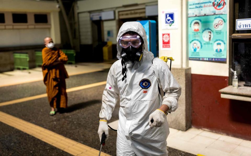 A cleaner wearing personal protective equipment disinfects Hua Lamphong railway station in Bangkok - AFP