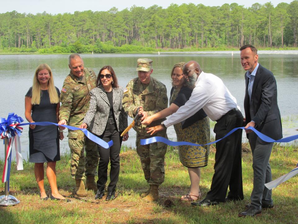 Representatives of Fort Bragg, Duke Energy and  Ameresco reveal the completion of a floating solar panel project on nearly 2 surface acres of Big Muddy Lake at Camp Mackall during a ceremony Friday, June 10, 2022.