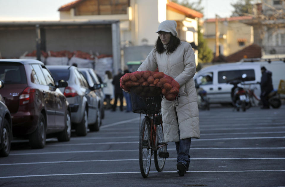 A customer pushing her bicycle loaded with a 10 kg sack of potatoes sold at an extremely low price (euro0.25 per kg) leaves an open market at the northern Greek town of Katerini, Greece on Saturday, Feb. 25 2012. Farmers in northern Greece have joined forces with local residents to provide cheap produce to people whose family budgets have been slashed by the financial crisis, and also to help producers who say they are being squeezed by middlemen. Hundreds of families turned up Saturday in this northern Greek town to buy potatoes at massively reduced prices, sold directly by producers at cost price. (AP Photo/Nicolas Giakoumidis)