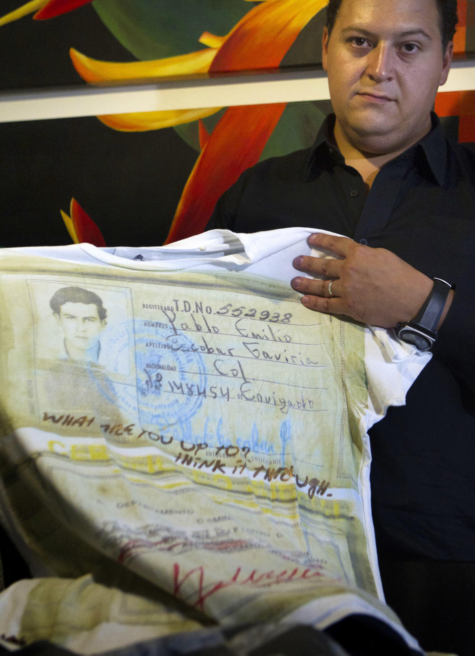 Sebastian Marroquin, son of Colombia's late drug lord Pablo Escobar, shows a shirt from his new clothing line "Escobar Henao," covered with an image of his father's identity card and reads "What are you up to? Think it through," at his home in Buenos Aires, Argentina, Friday, Aug. 17, 2012. Marroquin, who legally changed his name and moved to Argentina in 1994 with his mother Maria Valeria Henao after his father was killed, says he created the collection as a way to send a message of peace and reflection about his family's history. (AP Photo/Eduardo Di Baia)