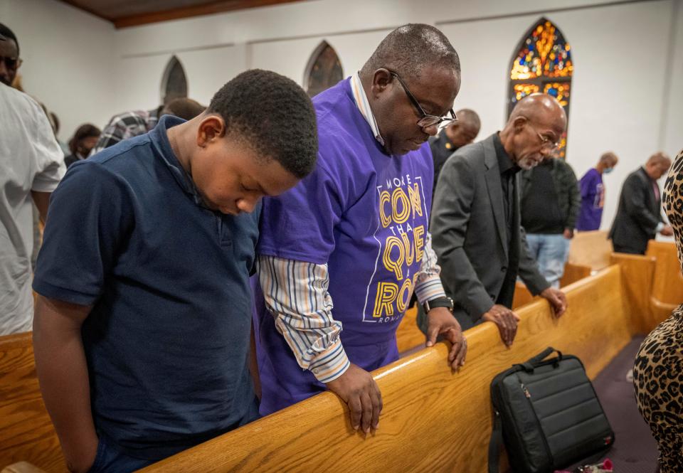 Dennis Anderson,12, prays with his father Joseph Anderson at the end of a town hall meeting with West Palm Beach Police Chief Adderley at New Bethel Missionary Baptist Church in West Palm Beach, Florida on January 31, 2023.