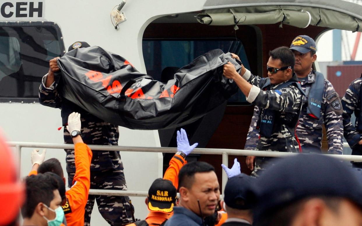 Rescuers remove a body bag containing remains of a victim in Monday's Lion Air plane crash - AP