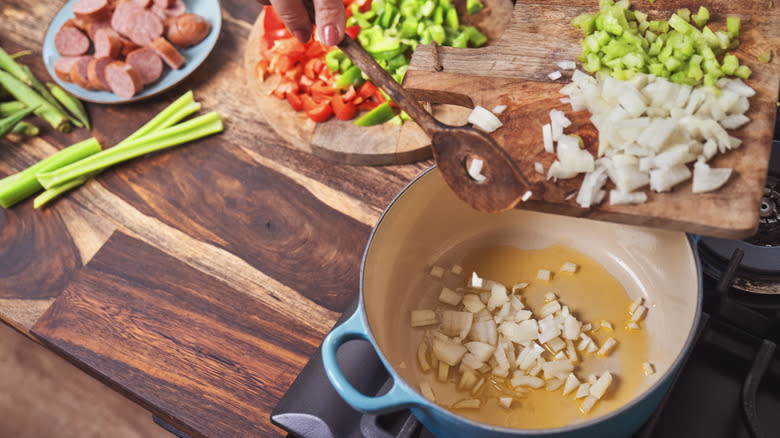 hand adding jambalaya ingredients to pot