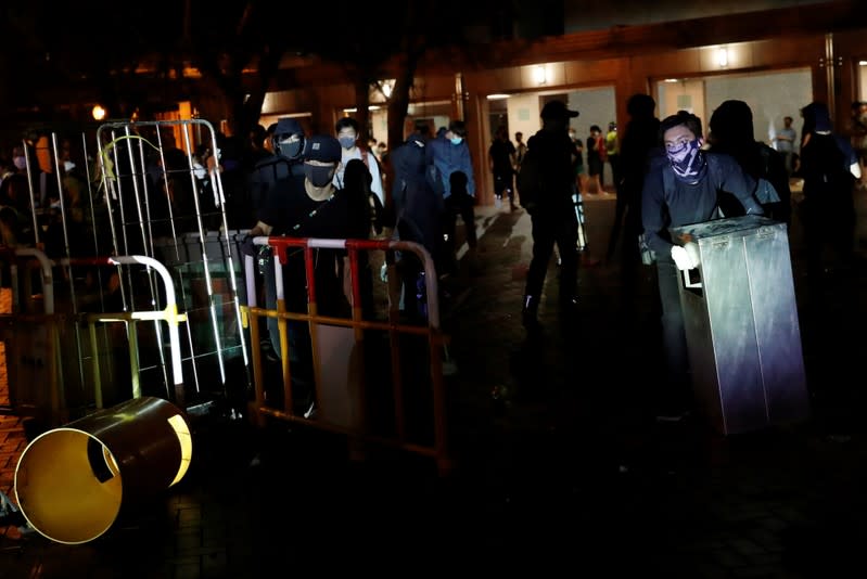 Anti-government protesters move object to take cover during a protest, following 22 year-old University student's fall and who was critically injured last weekend, in Tseung Kwan O, Hong Kong