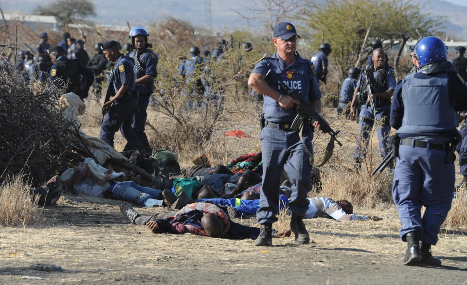 Police surround the bodies of striking miners after opening fire on a crowd at the Lonmin Platinum Mine near Rustenburg, South Africa, Thursday, Aug. 16, 2012. An unknown number of people have been killed and injured when police moved in on workers who gathered on a rocky outcrop near the Lonmin late afternoon, firing unknown ammunition. (AP Photo)