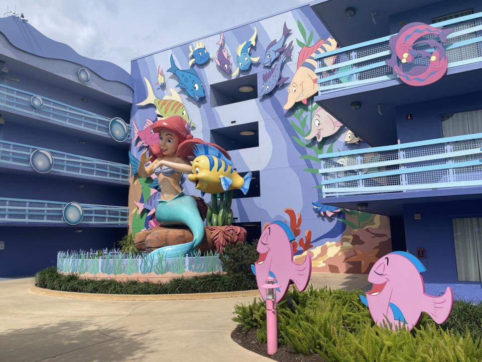little mermaid statue and decor in front of a building at disney's art of animation resort