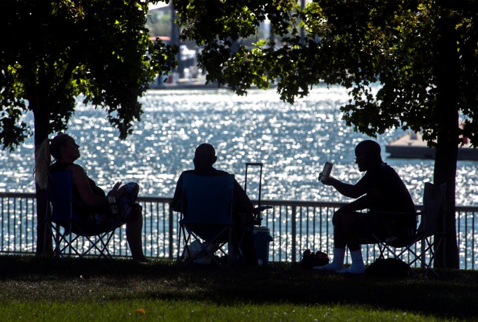 People sit under the shade of some trees at the Weber Point Events Center in an effort to finds one relief from the heat in downtown Stockton on Jul. 24, 2018.