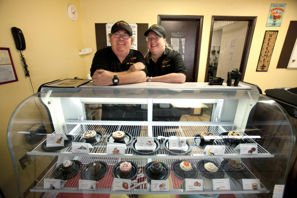 In this Wednesday, Aug. 1, 2012 photo, Michael, left, and Eve Dobbins stand by a display case at their store, Cupcake Cache, in Tampa, Fla. They opened Cupcake Cache in April. Money is so tight for the couple that he sold his golf clubs. Eve Dobbons recently took a college teaching job to supplement their income from the business, but both are convinced that with leases so cheap, they made the right move. (AP Photo/John Raoux)