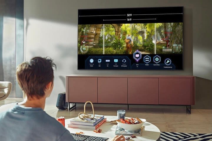 A man watching the Samsung 75-inch Q84A in his living room.
